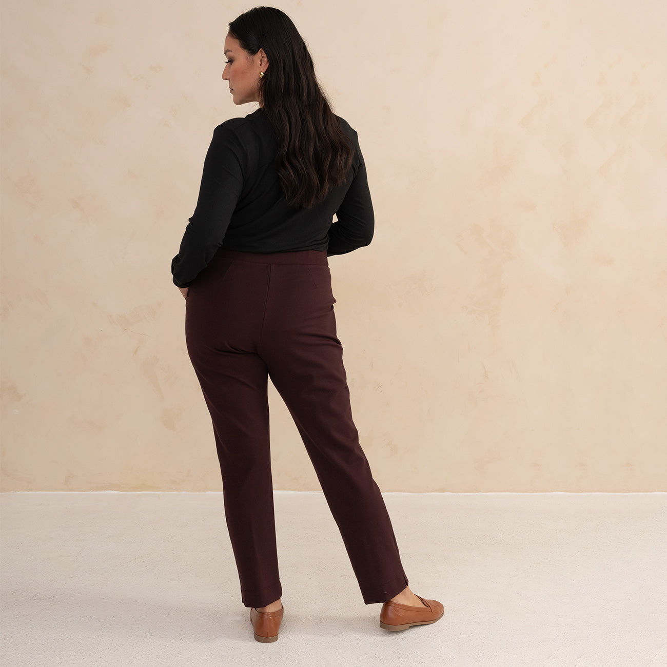 woman wearing a black longsleeve top an aubergine tailored pants