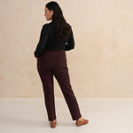 woman wearing a black longsleeve top an aubergine tailored pants