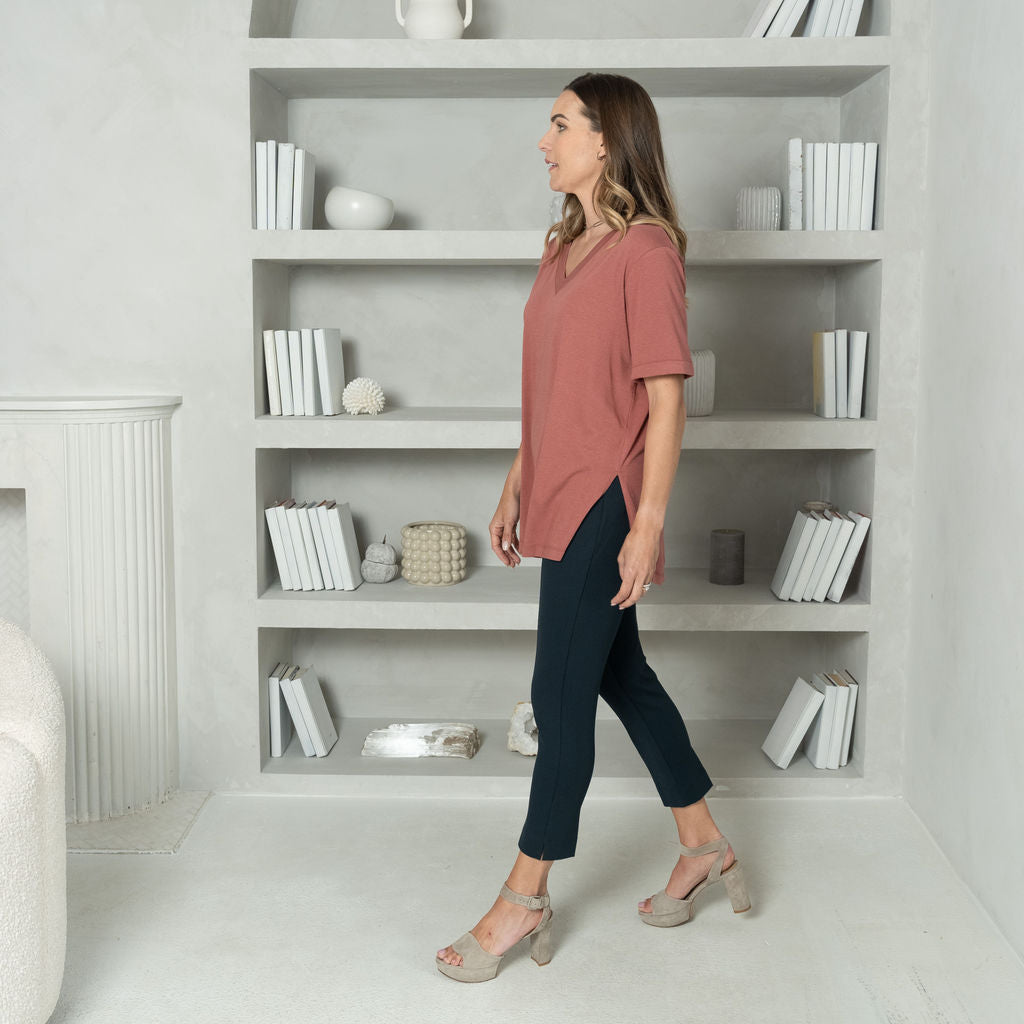 woman wearing a pink short sleeve t-shirt with ankle length navy tailored pants with two pockets