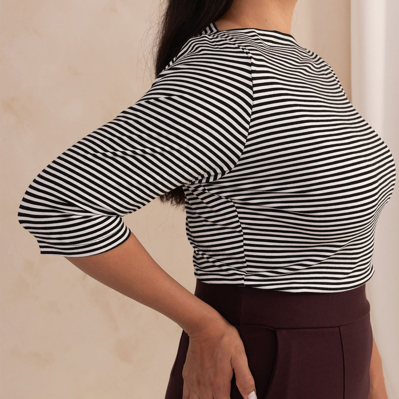side of a woman wearing a black and white stripes boat neck top 