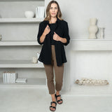 woman wearing a black short sleeve t-shirt, with a black long sleeve button-up and an ankle length brown tailored pants with two pockets