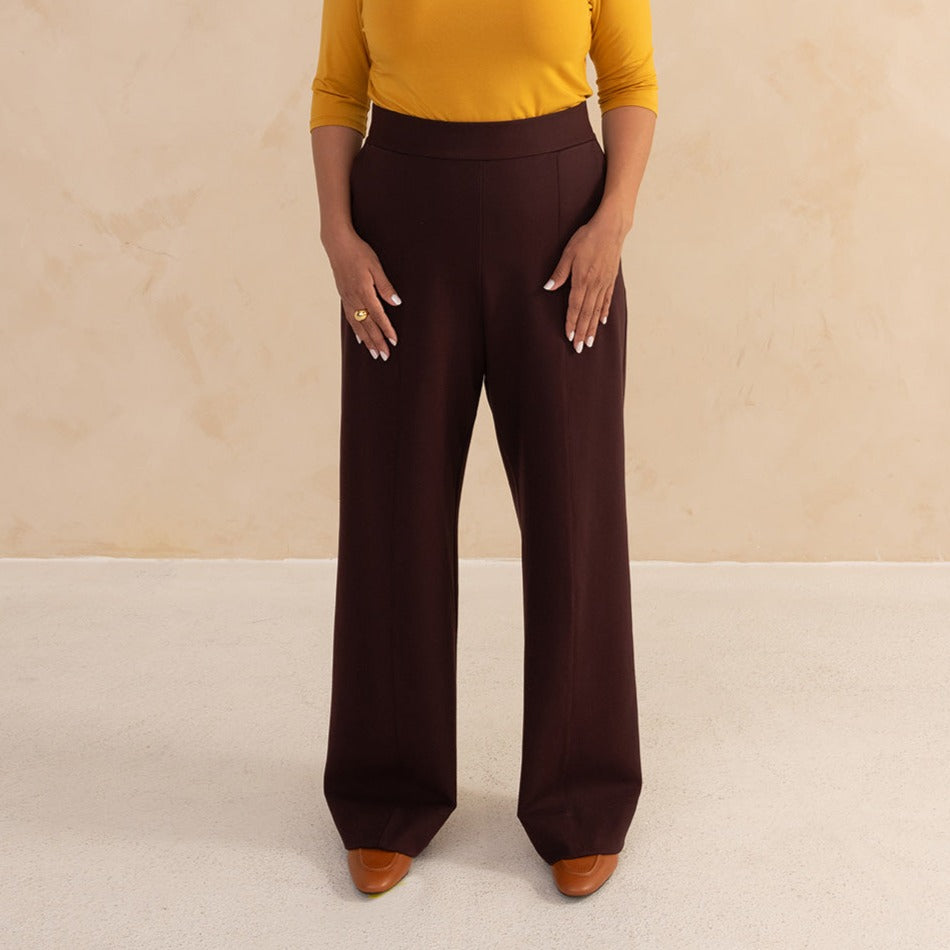 woman wearing a yellow 3/4 sleeve length and aubergine high waisted wide leg pants