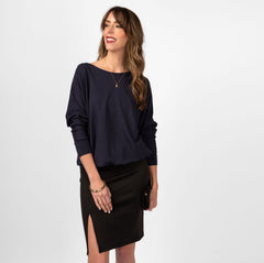 Woman wearing loose navy blue scoop neckline sweatshirt with black skirt