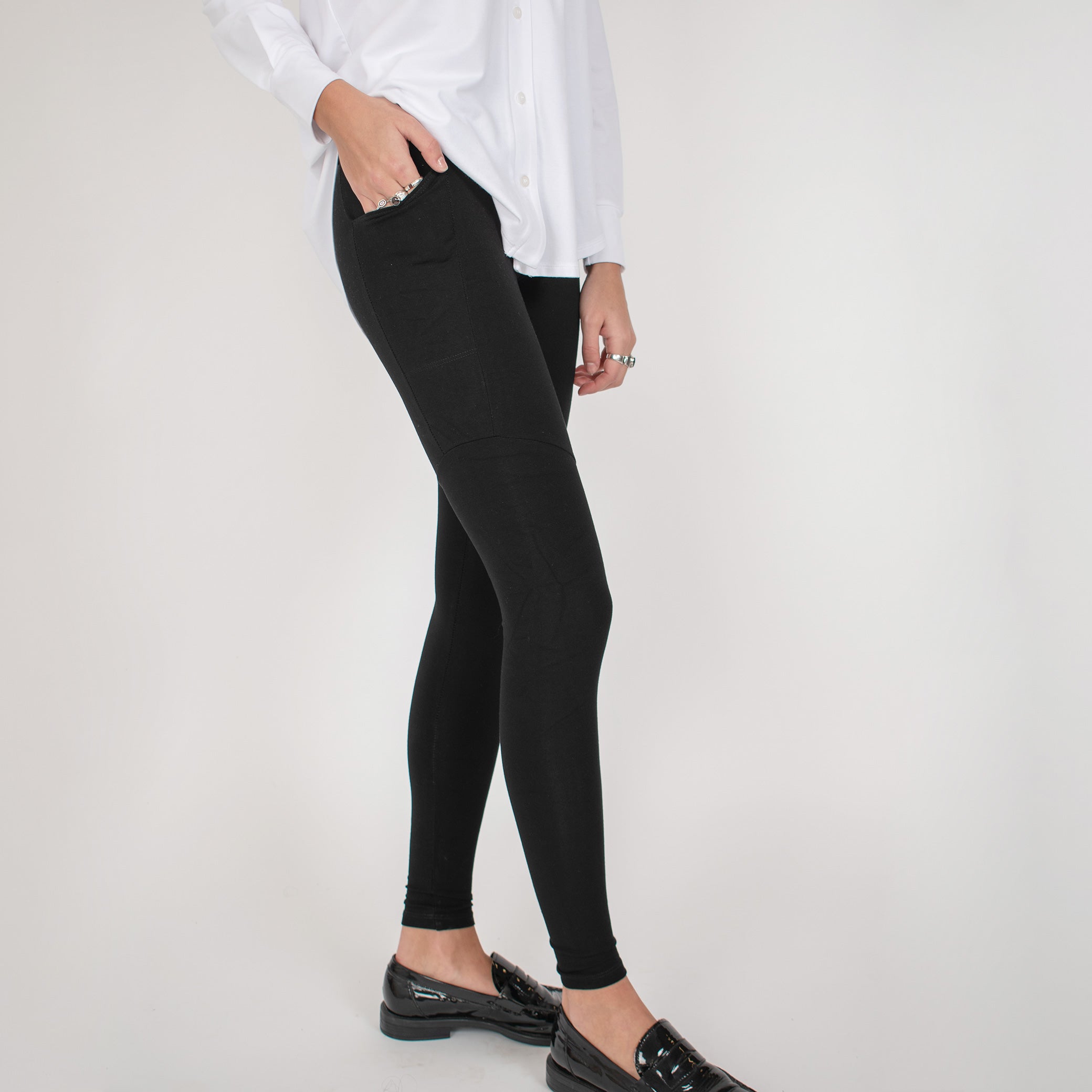 Woman wearing black form fitting stretchy leggings with hip pocket with white button up shirt