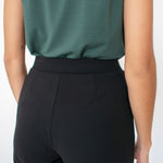 Woman wearing black tailored stretchy ankle length pants paired with tucked in green shirt